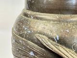a brown vase with a bird on it sitting on a table