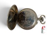 a silver pocket watch with a chain on a white surface