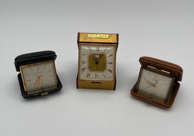 trois horloges miniatures posées les unes à côté des autres sur une surface blanche