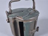 a small metal container with a handle on a white surface