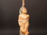 une statue représentant un homme tenant une bouteille posée sur une table