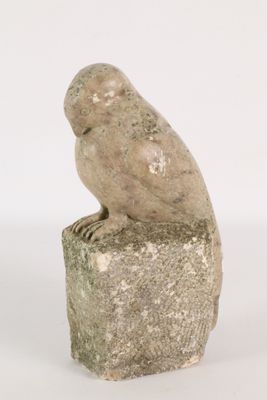statue of an owl sitting on a rock on a white background