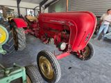 a man standing next to a red tractor in a garage