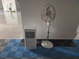 a fan sitting next to a small air conditioner on the floor