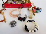 une boîte rouge remplie de bijoux variés, posée sur une table blanche