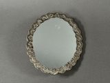 miroir plaqué argent avec un bord festonné sur un fond gris