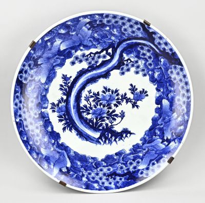 une assiette bleue et blanche décorée d'un arbre et de fleurs