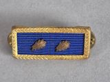a close up of a blue and gold pin with two birds on it