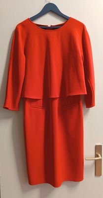 une robe rouge accrochée au mur près d'une porte