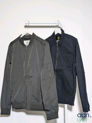 two jackets hanging on a clothes rack in a white room