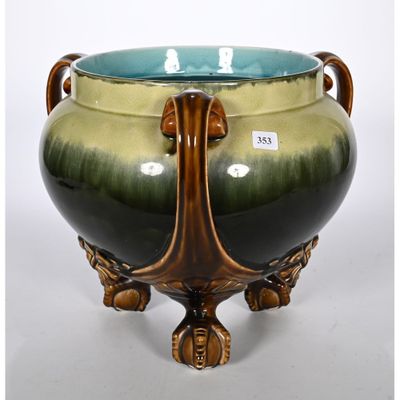 un vase vert et marron posé sur un socle