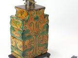 a green and orange vase with a brass faucet on top of it