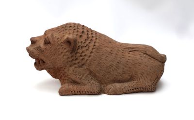 une petite figurine représentant un lion posée sur une surface blanche
