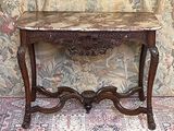 une table au plateau en marbre posée sur un tapis devant un papier peint à motifs floraux