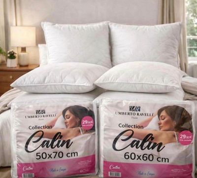 two pillows on top of a bed in a bedroom next to a window