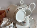 a person holding a cup and saucer over a stack of dishes