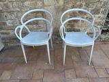 two white chairs sitting next to each other on a brick floor