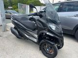 a black scooter parked in a parking lot next to a car