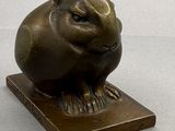 a bronze sculpture of a rabbit on a wooden base