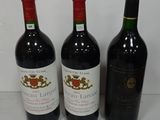 three bottles of red wine are lined up on a table