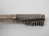 a close up of a brush with a metal handle on a white surface