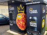 deux distributeurs automatiques sur lesquels figurent des pizzas, situés devant un immeuble