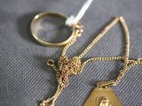 a gold necklace and a gold ring on a gray cloth