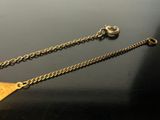 a gold necklace with a triangle on it on a table
