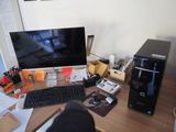 a desk with a computer, keyboard, mouse, and other items on it