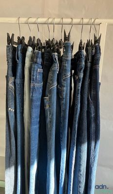 several pairs of blue jeans hanging on a rack in a store