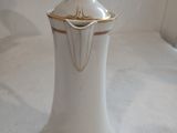 a white and gold coffee pot sitting on a white table