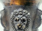 a close up of a metal vase with a lion head on it