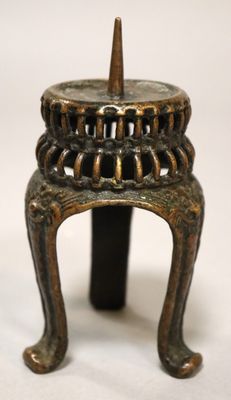 an image of a small bronze candle holder with a candle on top of it