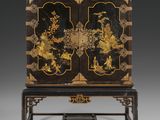 a black and gold decorated cabinet on stand