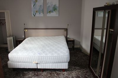 un lit qui se trouve dans une chambre où il y a un miroir accroché au mur