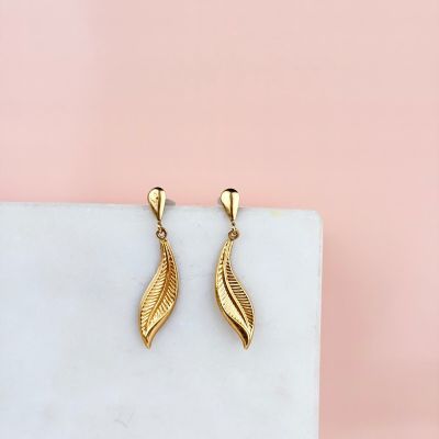 a pair of gold earrings on a marble block