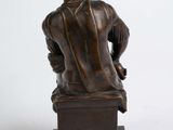 bronze statue of a man sitting on a box with his back turned to the camera