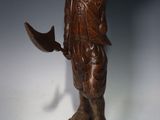 une image représentant une statue en bois d'un homme portant un chapeau et une épée