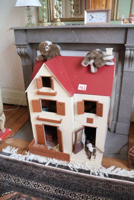 une maison de poupées sur le toit de laquelle sont assis un chien et un chat
