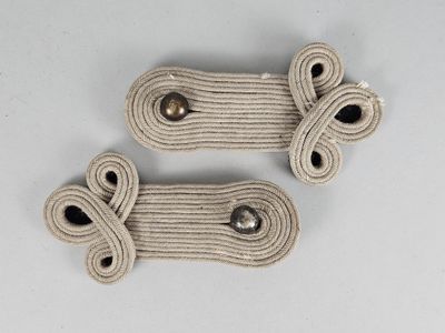 deux cordes blanches et des boutons métalliques sur une surface blanche