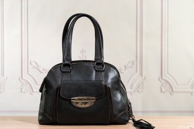 black leather handbag sitting on a table in front of a wall
