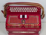 an old red accordion sitting on top of a white table