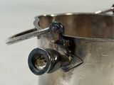 a silver cup with a metal handle on a table