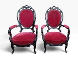 une paire de fauteuils en velours rouge aux accoudoirs sculptés