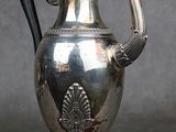 une théière en argent avec une anse en forme de paon, posée sur un socle