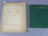 an old book and a green book sitting on top of a table