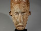 tête d'homme sculptée posée sur un socle noir, sur fond blanc