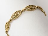 a close up of a gold bracelet on a white surface