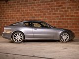 a silver sports car parked in front of a brick wall