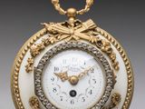 une image représentant une horloge dorée et blanche, avec une chaîne autour du cadran